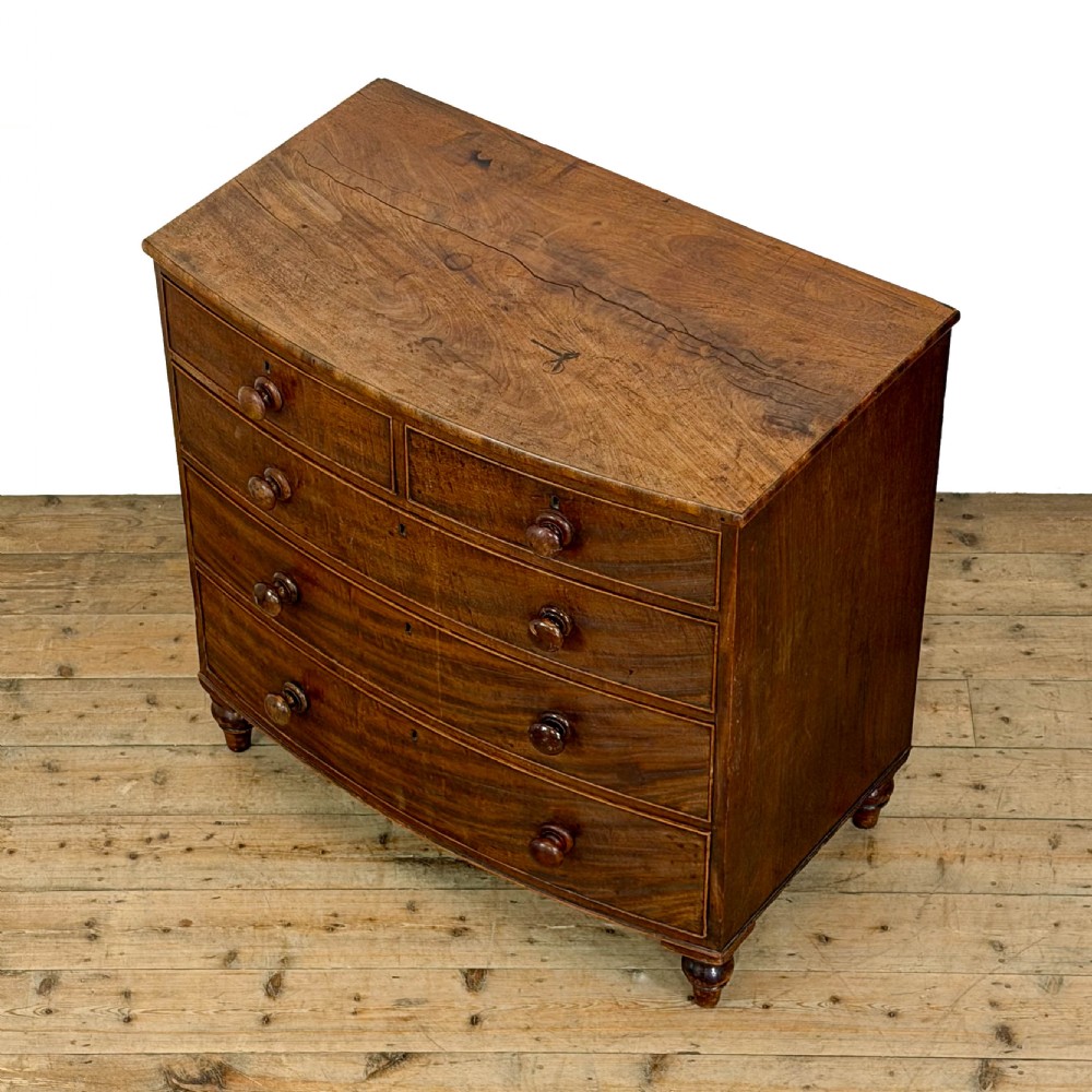 An antique mahogany bow front chest of drawers with two short drawers over three long graduated drawers, turned wooden handles, and turned feet. View IV