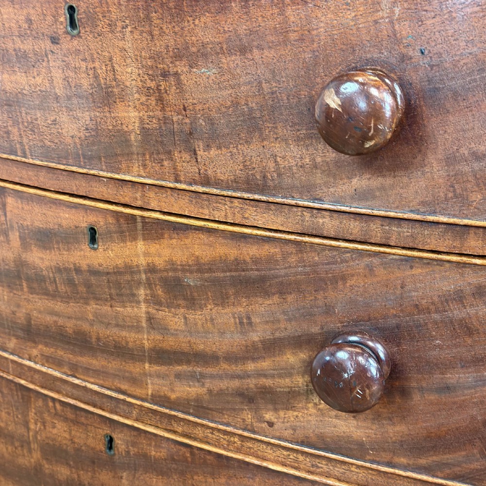 An antique mahogany bow front chest of drawers with two short drawers over three long graduated drawers, turned wooden handles, and turned feet. View X