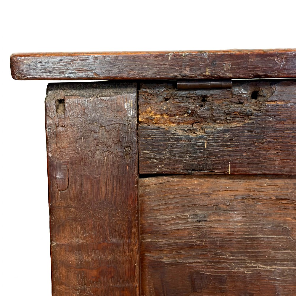 An 18th-century dark oak coffer featuring three carved front panels, a carved floral frieze, a hinged top lid, and an iron lock plate. View VIII