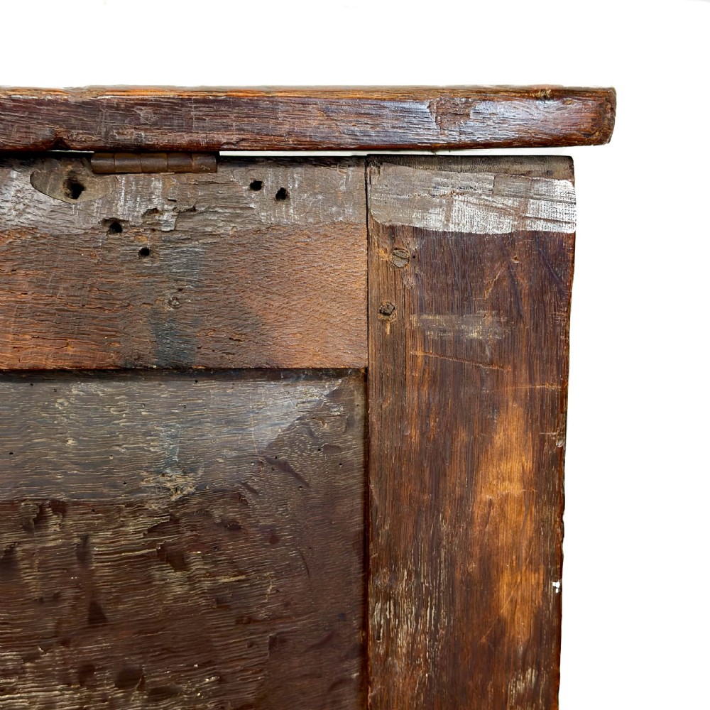 An 18th-century dark oak coffer featuring three carved front panels, a carved floral frieze, a hinged top lid, and an iron lock plate. View IX