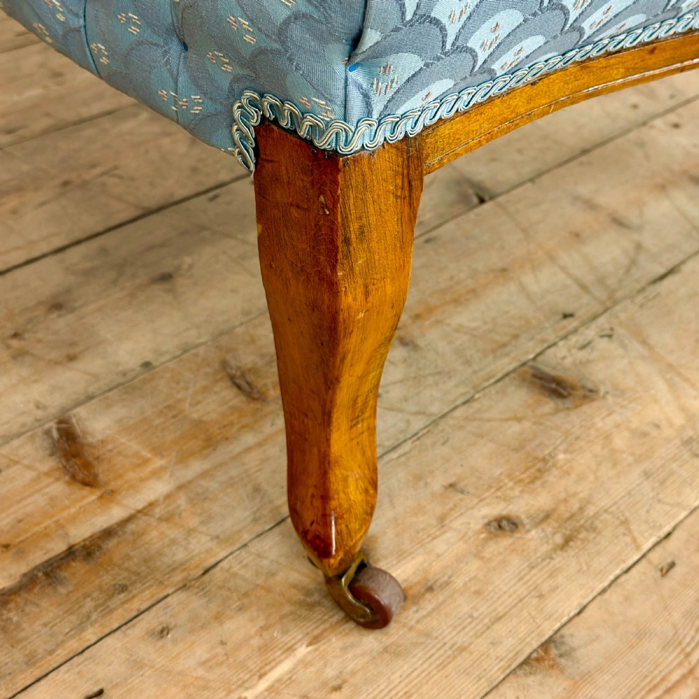 An Edwardian mahogany tub armchair with light blue pattern fabric upholstery, deep-buttoned backrest, and legs on castors. View VII