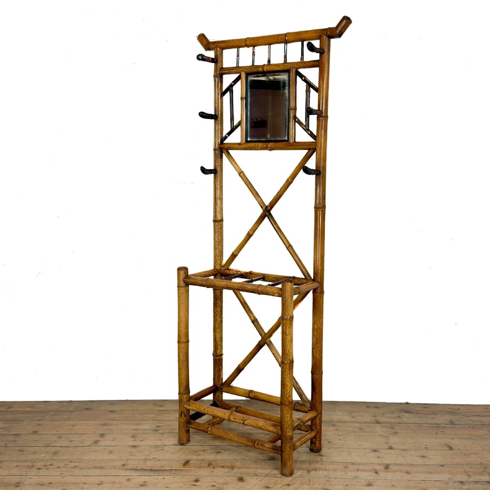 A tall Victorian bamboo hall stand featuring a central rectangular mirror, multiple turned coat pegs, cross-braced framing, and an integrated stick stand base. View II