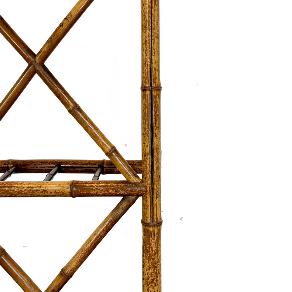 A tall Victorian bamboo hall stand featuring a central rectangular mirror, multiple turned coat pegs, cross-braced framing, and an integrated stick stand base. View VI