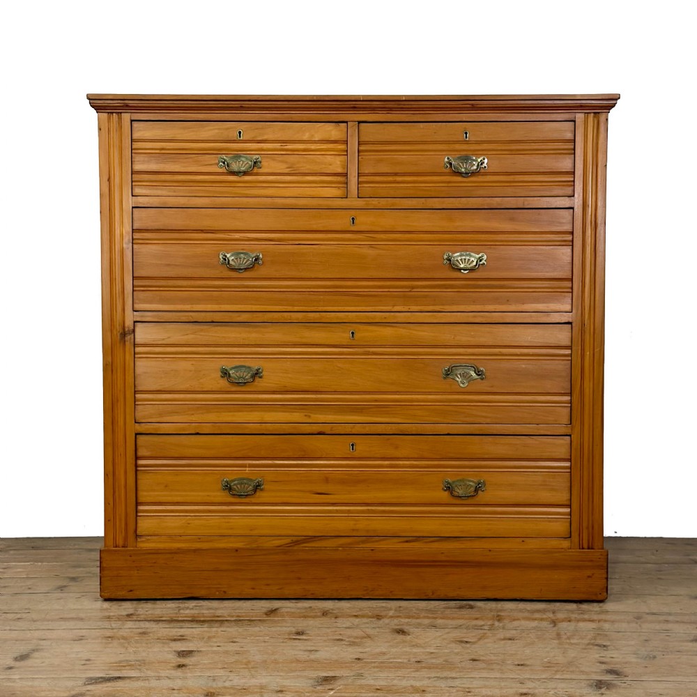 An Edwardian pine chest of drawers featuring two short drawers above three long drawers with reeded drawer fronts and brass cup handles.