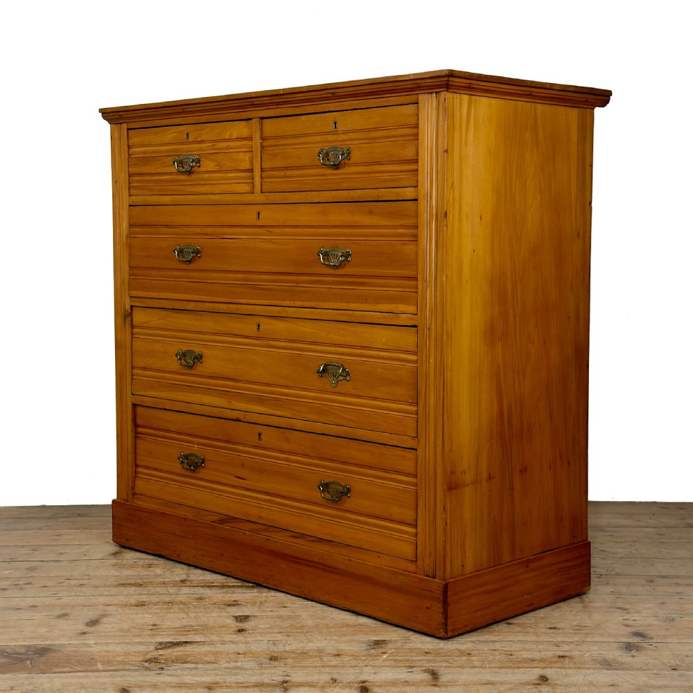 An Edwardian pine chest of drawers featuring two short drawers above three long drawers with reeded drawer fronts and brass cup handles. View IV
