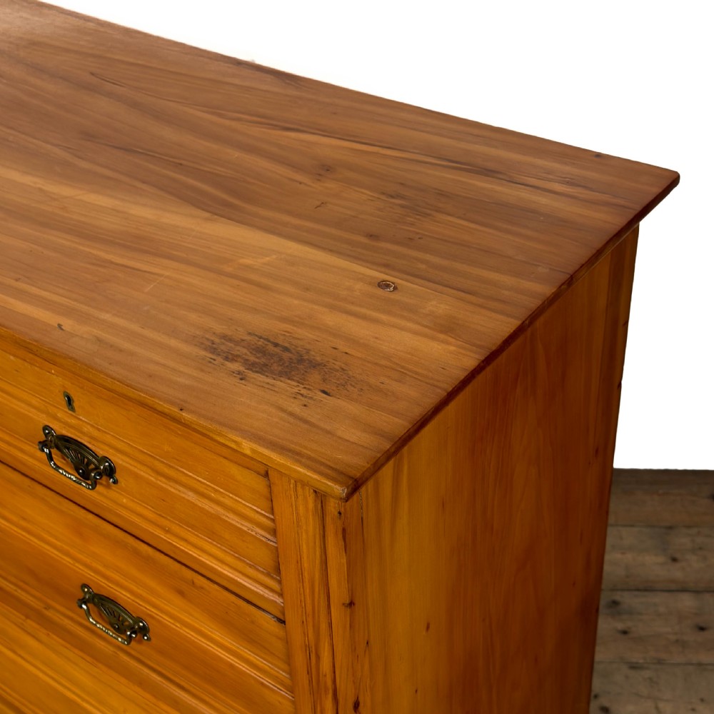An Edwardian pine chest of drawers featuring two short drawers above three long drawers with reeded drawer fronts and brass cup handles. View V