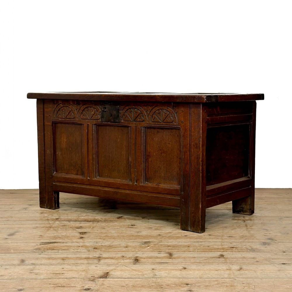 A dark oak coffer with three carved lunette frieze panels above recessed lower panels and an iron lock plate. View II