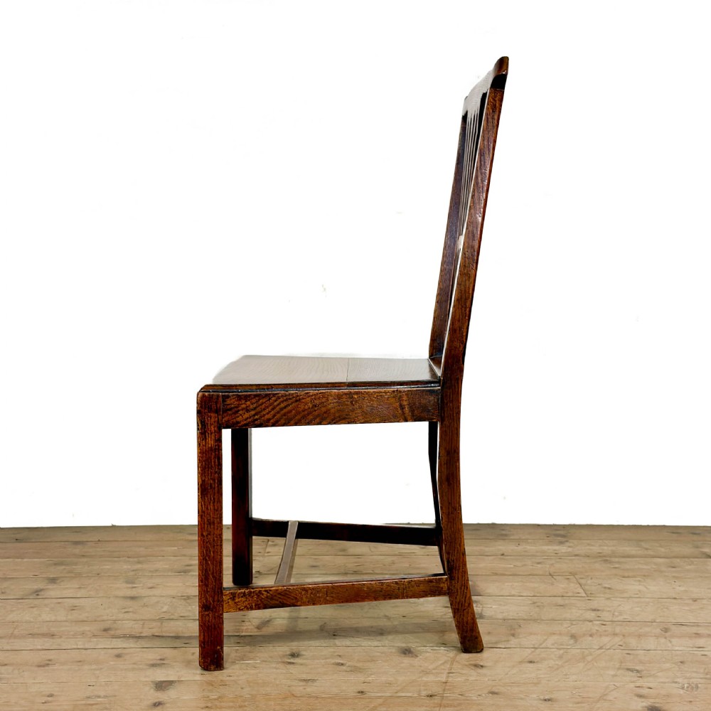 A set of six medium brown antique oak dining chairs featuring vertical splat backs, solid wooden seats, and stretcher bases. View V