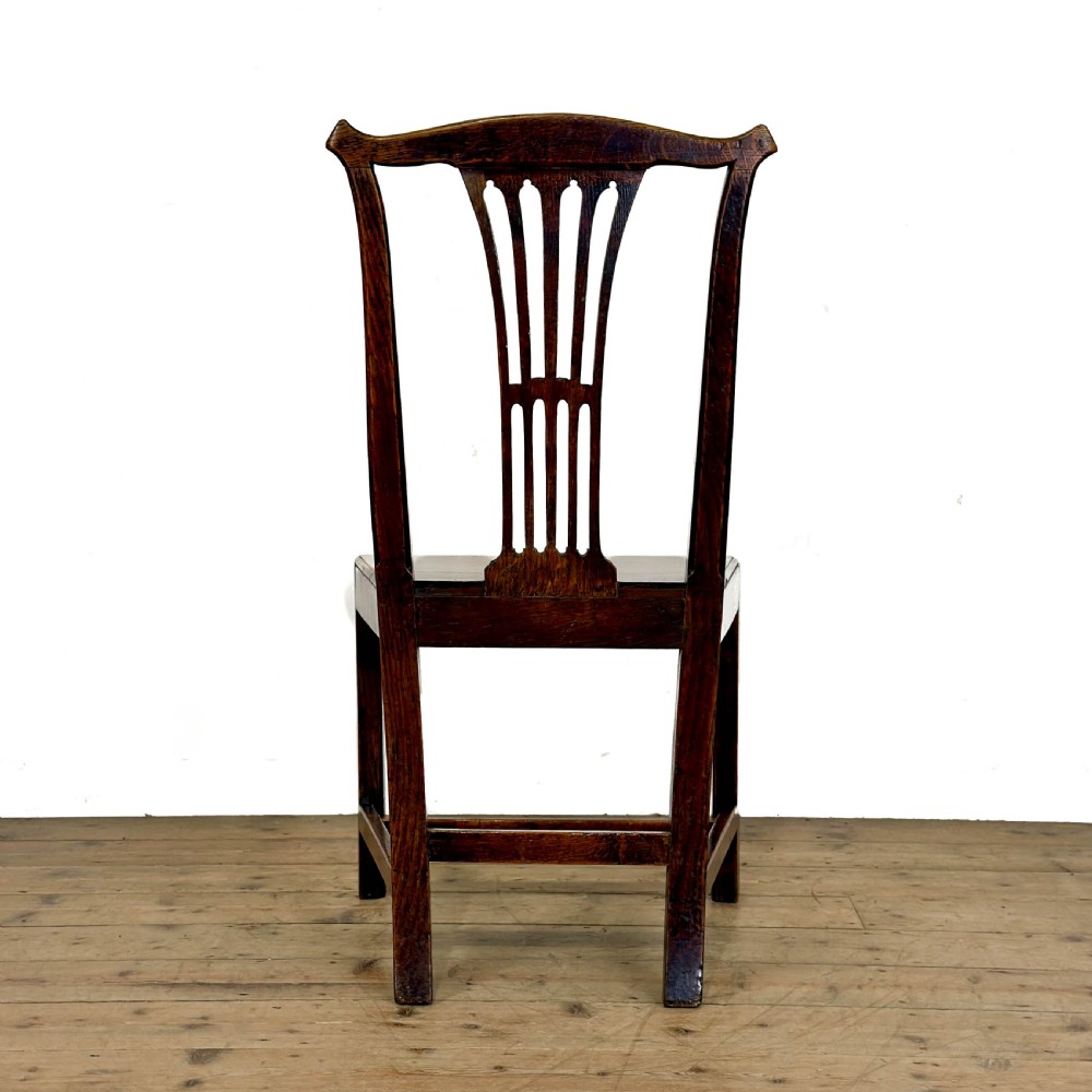 A set of six medium brown antique oak dining chairs featuring vertical splat backs, solid wooden seats, and stretcher bases. View VI