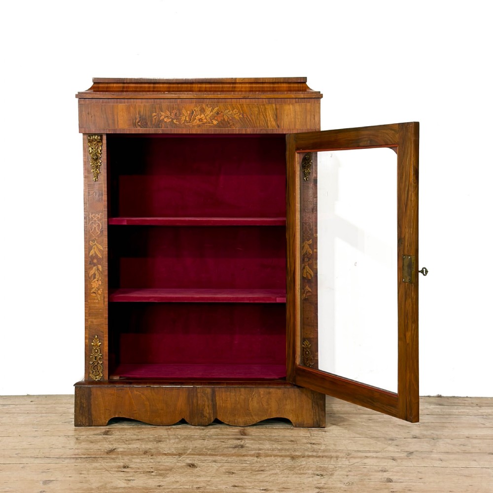 A Victorian walnut pier cabinet featuring floral marquetry inlays, gilt metal mounts, a single glazed door, and a red fabric-lined interior with two shelves. View II