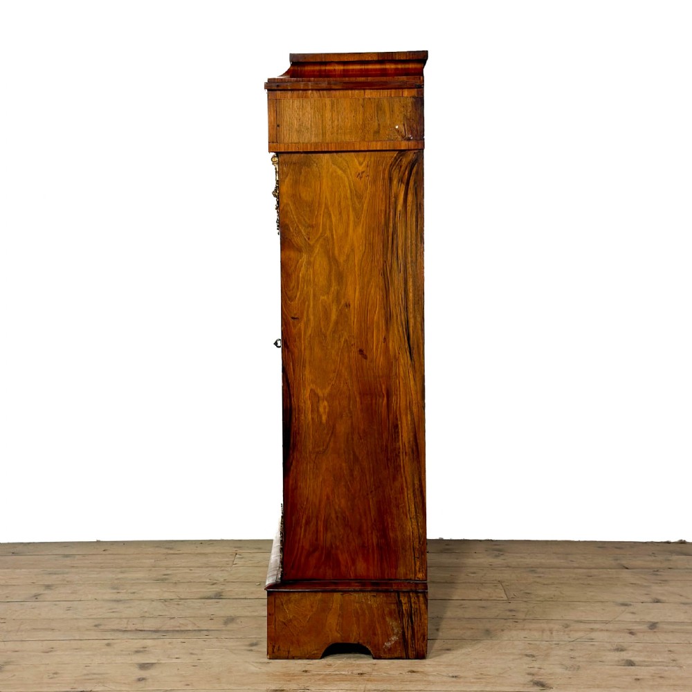 A Victorian walnut pier cabinet featuring floral marquetry inlays, gilt metal mounts, a single glazed door, and a red fabric-lined interior with two shelves. View VII