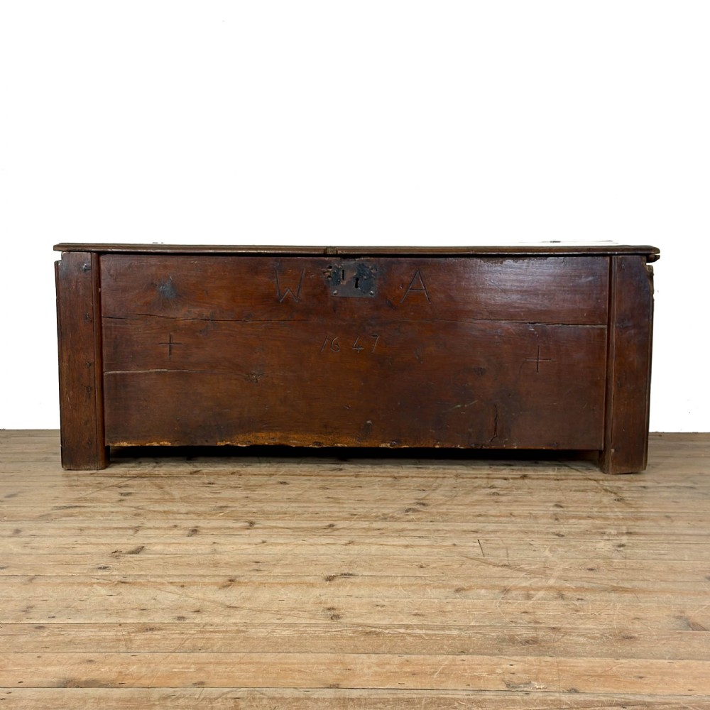A large dark oak coffer featuring the carved initials W A, the date 1647, two small carved crosses, and a central iron lockplate.