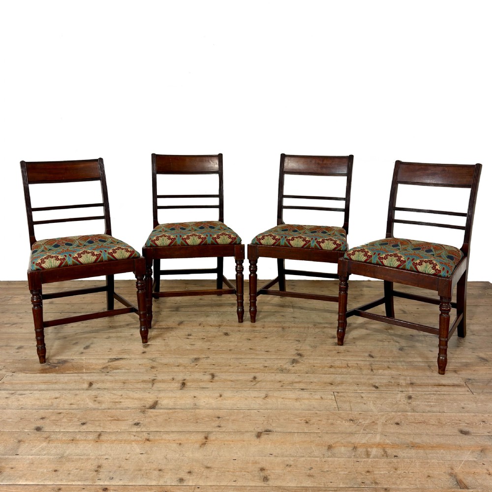 Set of four antique mahogany dining chairs with horizontal bar backs, turned front legs, and patterned drop-in upholstered seats.