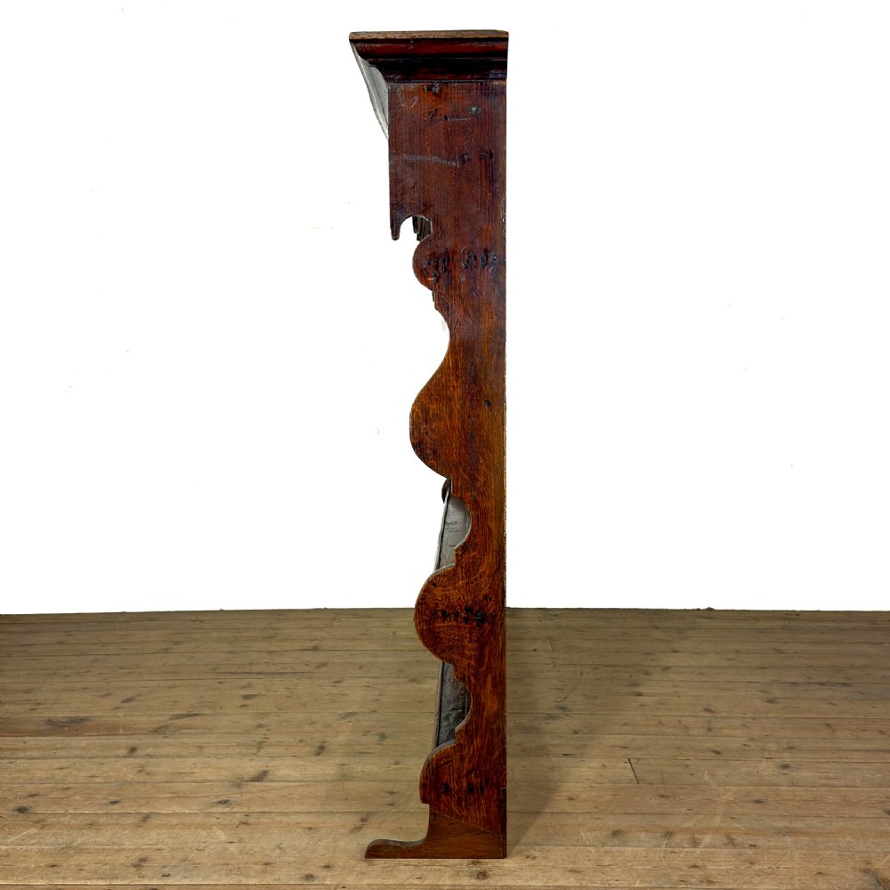 A dark oak wooden dresser rack featuring three horizontal shelves and a scalloped top frieze. View IV