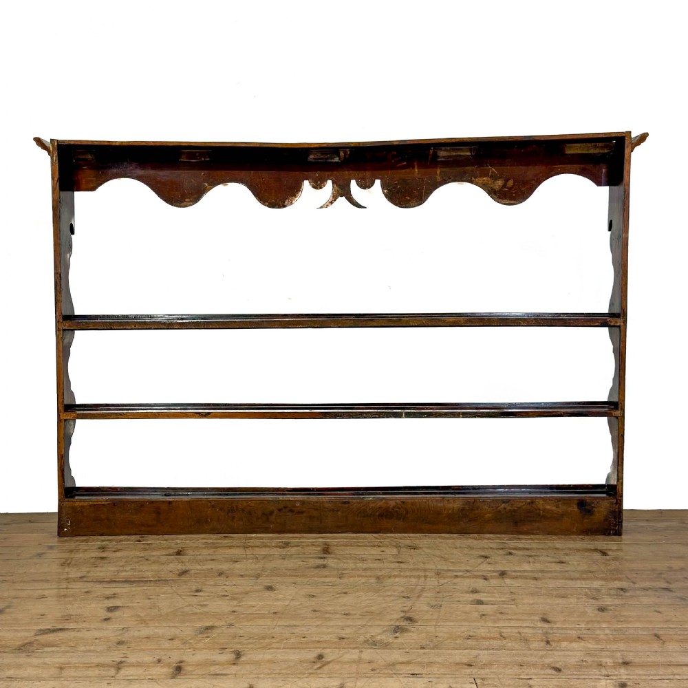 A dark oak wooden dresser rack featuring three horizontal shelves and a scalloped top frieze. View VI