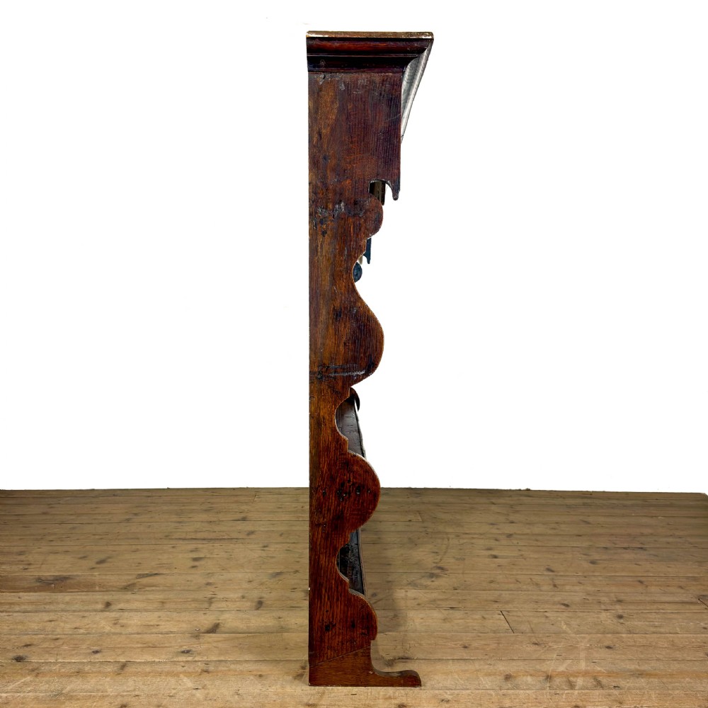A dark oak wooden dresser rack featuring three horizontal shelves and a scalloped top frieze. View VII