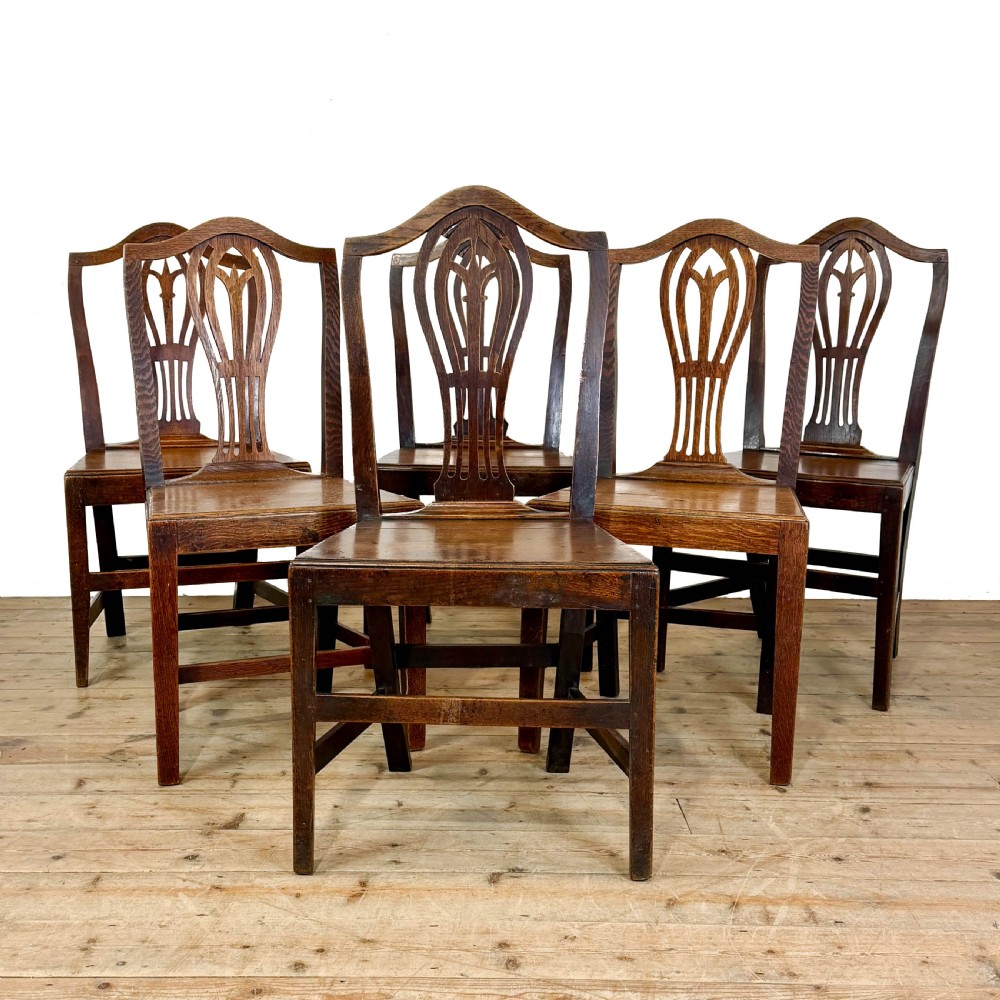 A set of six 19th-century oak dining chairs featuring pierced back splats, solid wooden seats, and straight legs connected by stretchers. View II