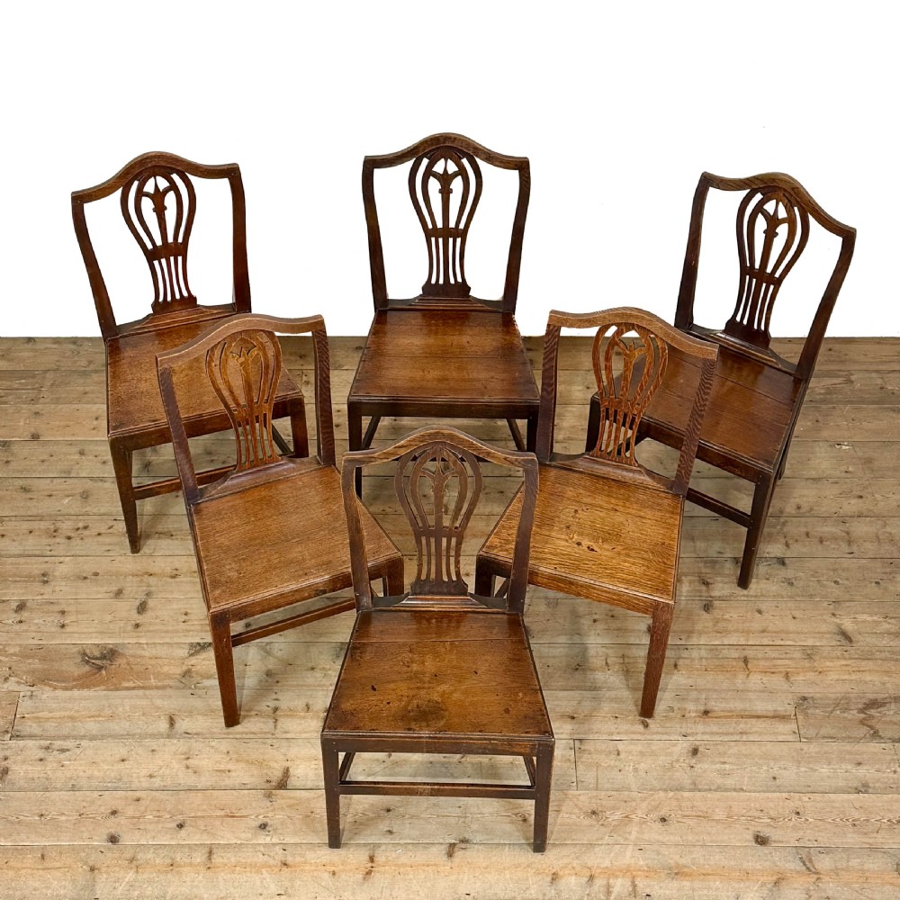 A set of six 19th-century oak dining chairs featuring pierced back splats, solid wooden seats, and straight legs connected by stretchers. View III
