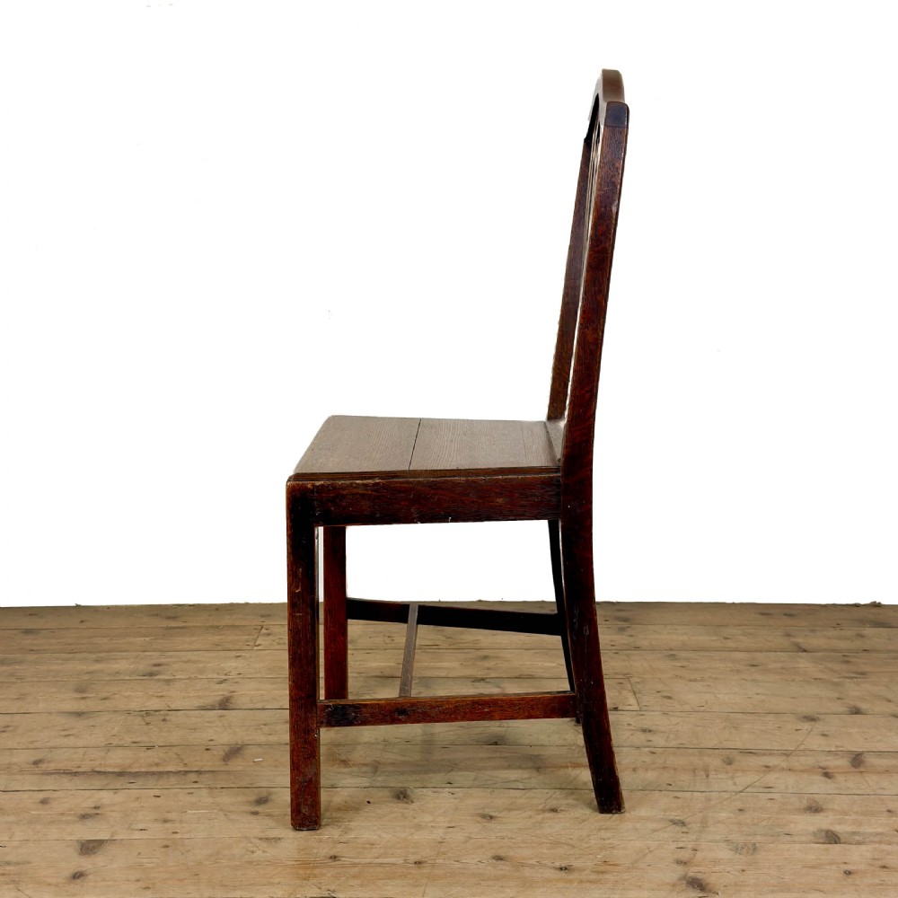 A set of six 19th-century oak dining chairs featuring pierced back splats, solid wooden seats, and straight legs connected by stretchers. View VI