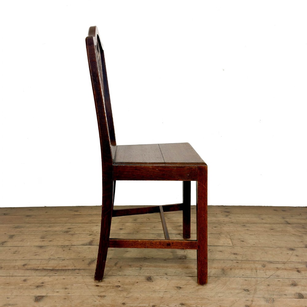 A set of six 19th-century oak dining chairs featuring pierced back splats, solid wooden seats, and straight legs connected by stretchers. View VIII