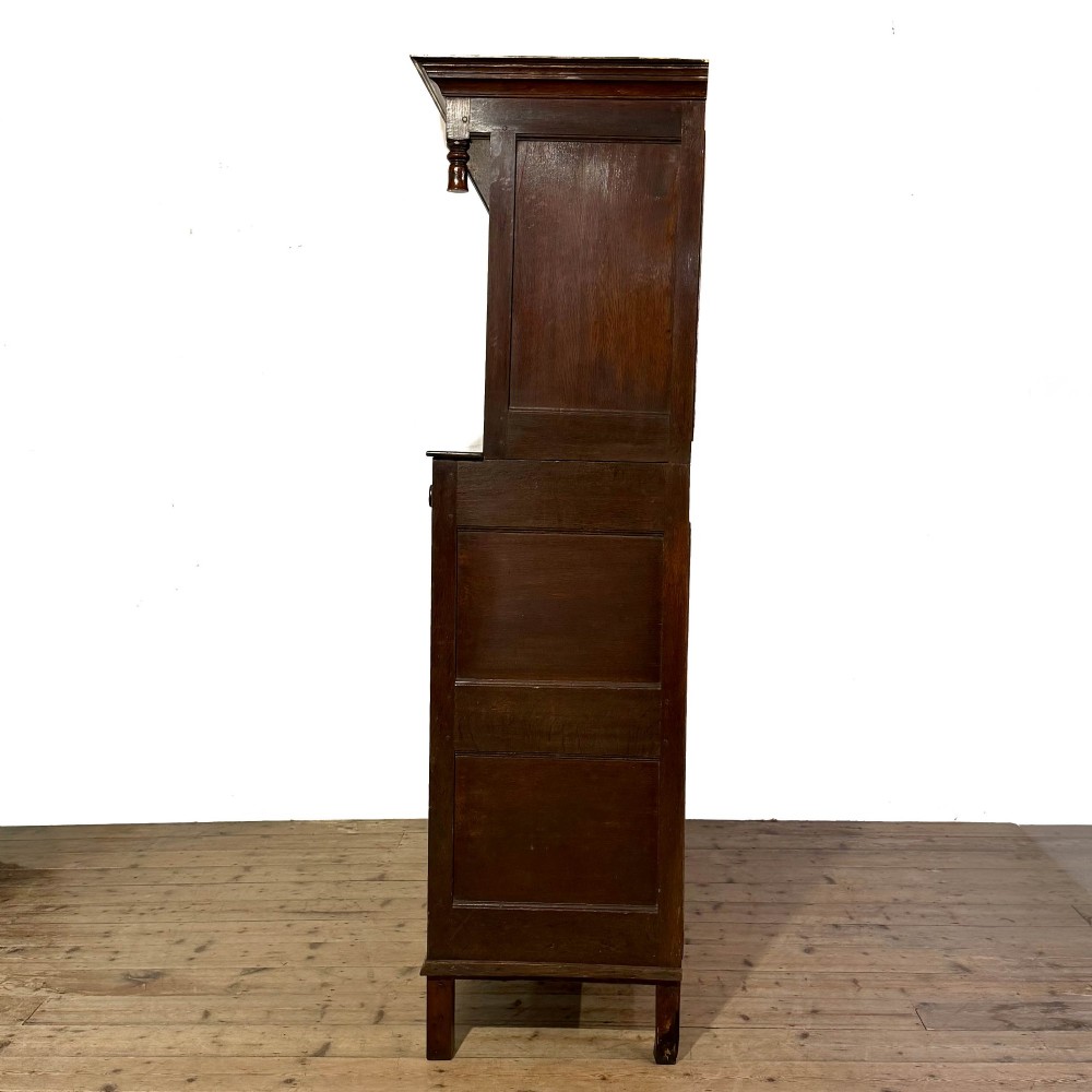 An 18th-century dark oak Welsh cwpwrdd deuddarn cupboard featuring two tiers with arched panelled doors and three lower drawers. View II