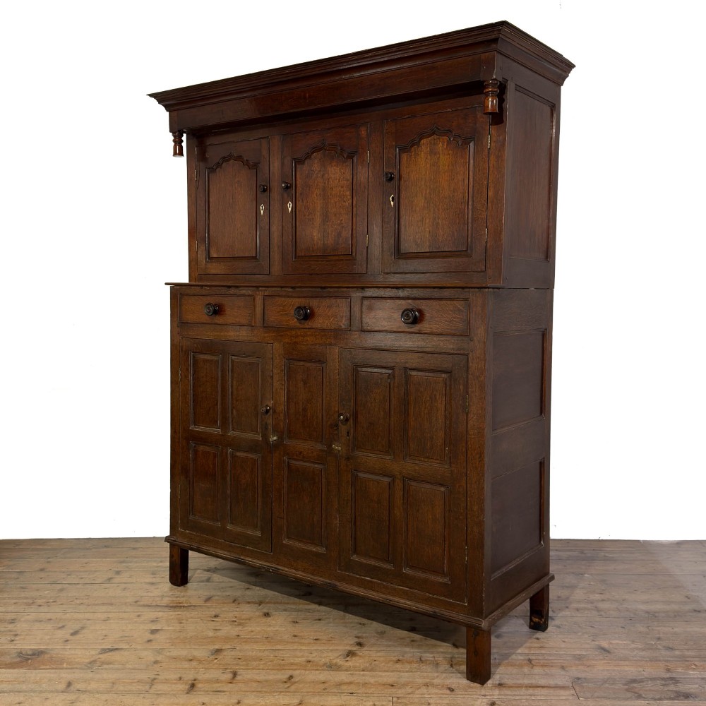 An 18th-century dark oak Welsh cwpwrdd deuddarn cupboard featuring two tiers with arched panelled doors and three lower drawers. View IV