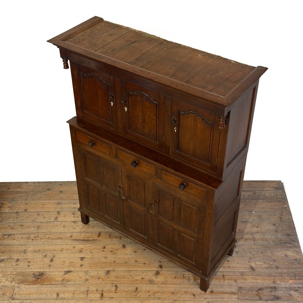 An 18th-century dark oak Welsh cwpwrdd deuddarn cupboard featuring two tiers with arched panelled doors and three lower drawers. View V