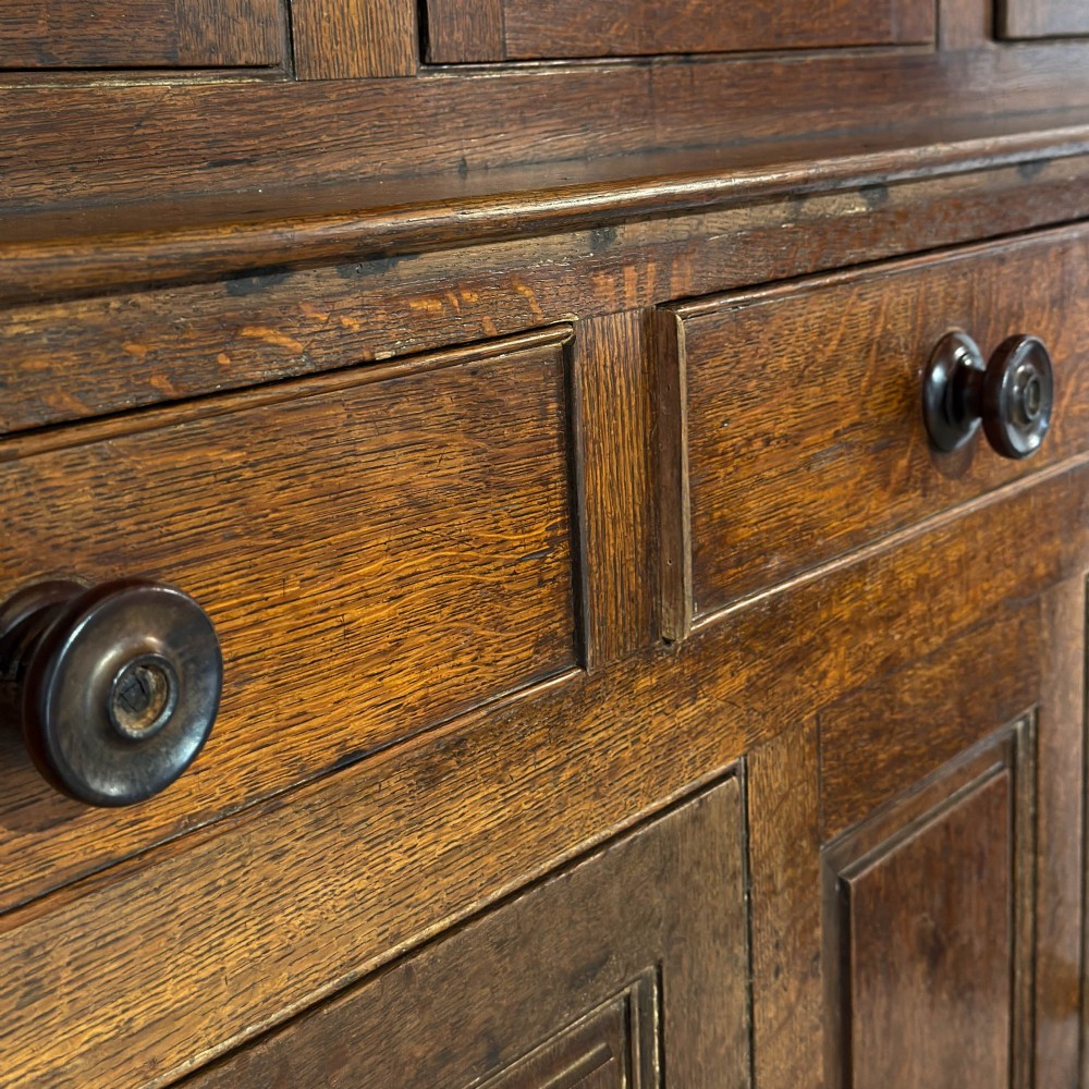 An 18th-century dark oak Welsh cwpwrdd deuddarn cupboard featuring two tiers with arched panelled doors and three lower drawers. View IX