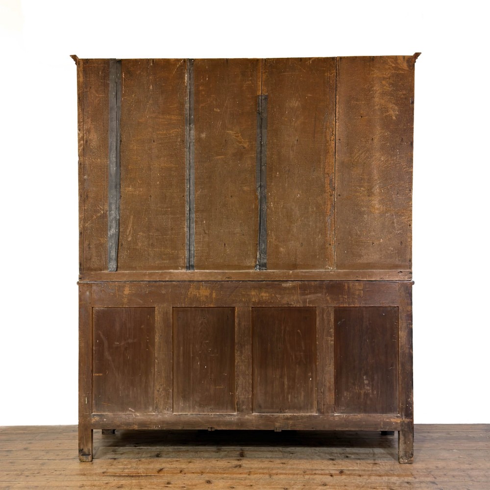 An antique 19th-century dark oak North Wales dresser featuring an open three-shelf plate rack with a pierced fretwork frieze above a base with two cupboards and four central drawers. View V