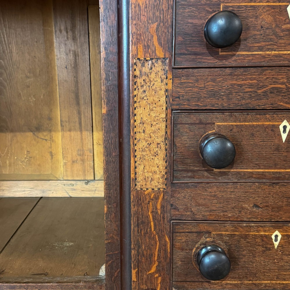 An antique 19th-century dark oak North Wales dresser featuring an open three-shelf plate rack with a pierced fretwork frieze above a base with two cupboards and four central drawers. View VI