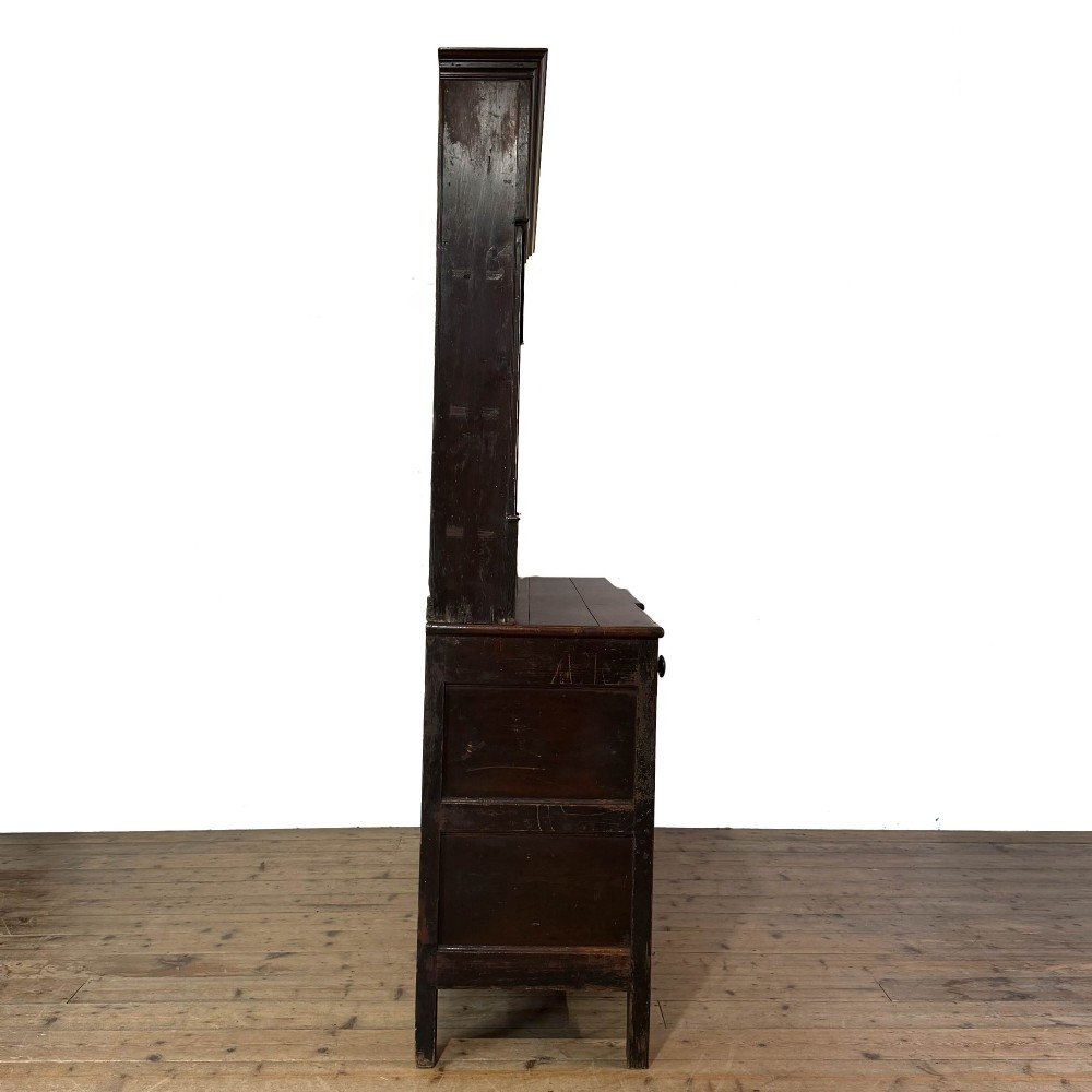 An antique 19th-century dark oak North Wales dresser featuring an open three-shelf plate rack with a pierced fretwork frieze above a base with two cupboards and four central drawers. View IX