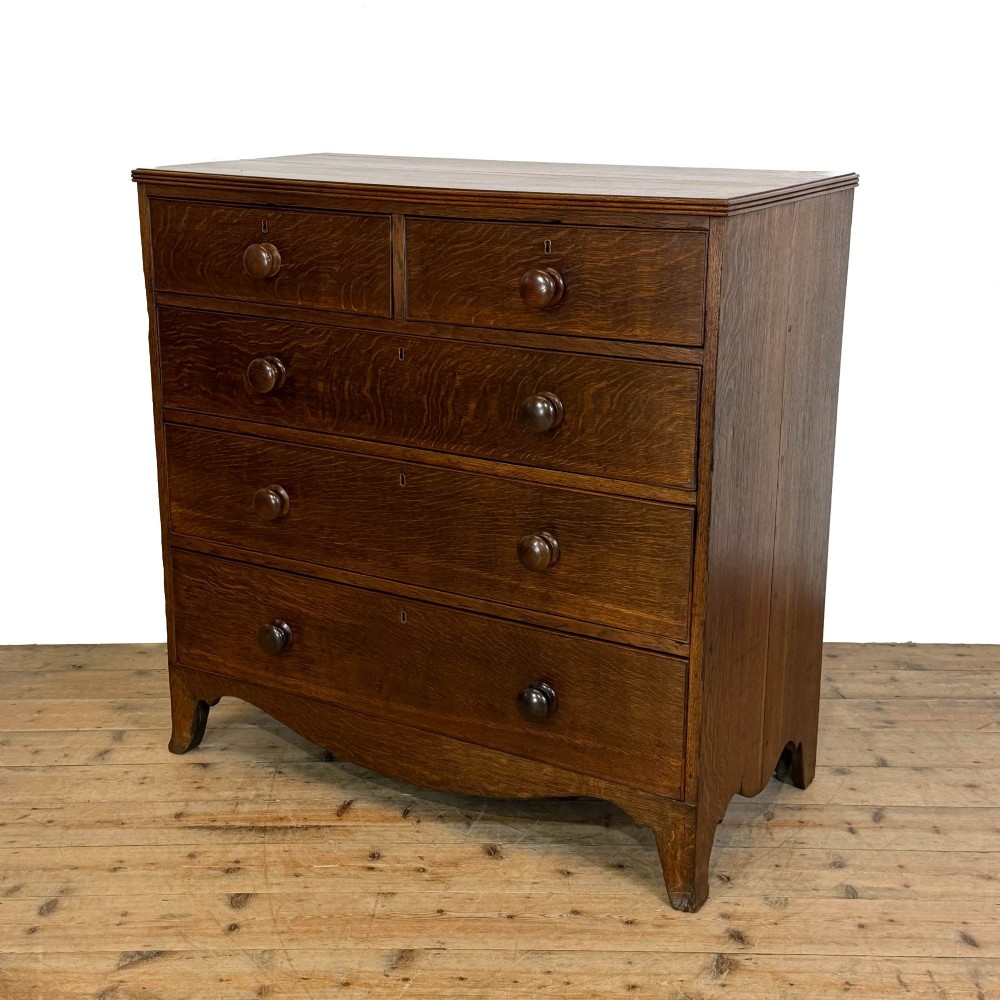 An antique Georgian oak chest of drawers featuring two short drawers over three long drawers with turned wooden knobs and a shaped apron. View II