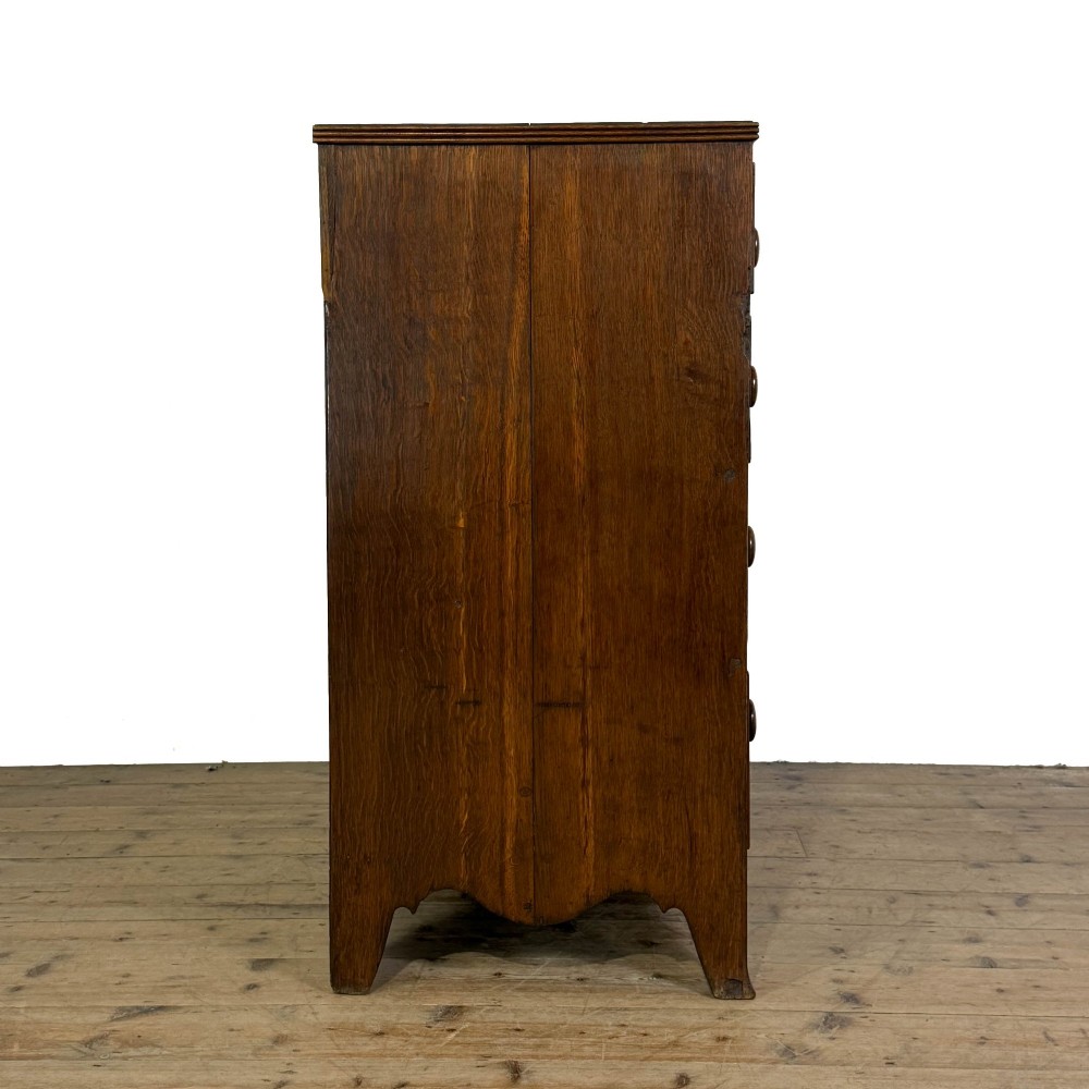An antique Georgian oak chest of drawers featuring two short drawers over three long drawers with turned wooden knobs and a shaped apron. View XI