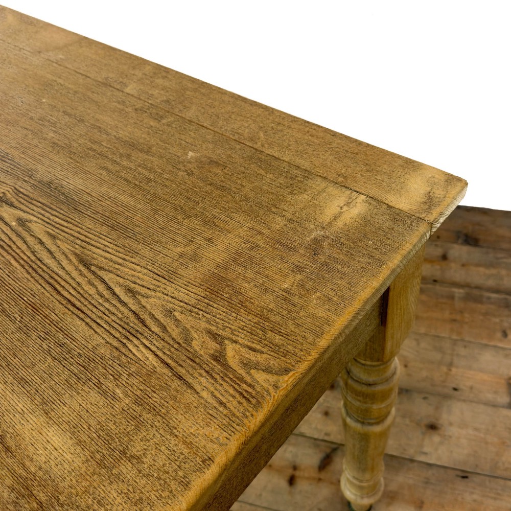 An antique stripped pine side table featuring two drawers with metal drop handles and four turned legs on castors. View V
