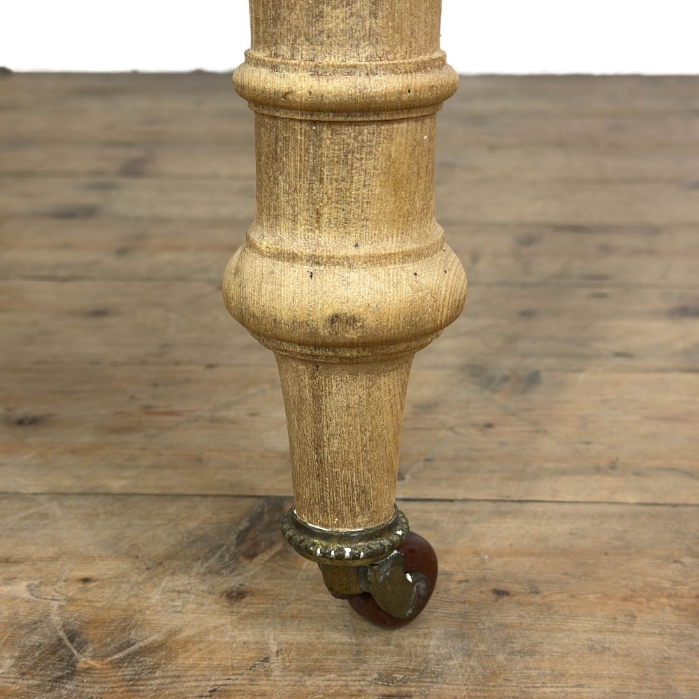 An antique stripped pine side table featuring two drawers with metal drop handles and four turned legs on castors. View VII