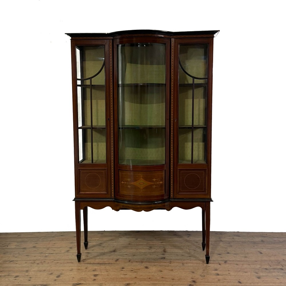An Edwardian mahogany display cabinet featuring a central bow-front glazed door with marquetry inlay flanked by two side glazed panels.