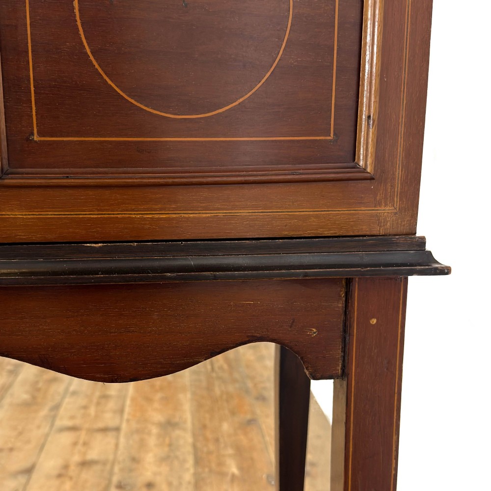 An Edwardian mahogany display cabinet featuring a central bow-front glazed door with marquetry inlay flanked by two side glazed panels. View IV