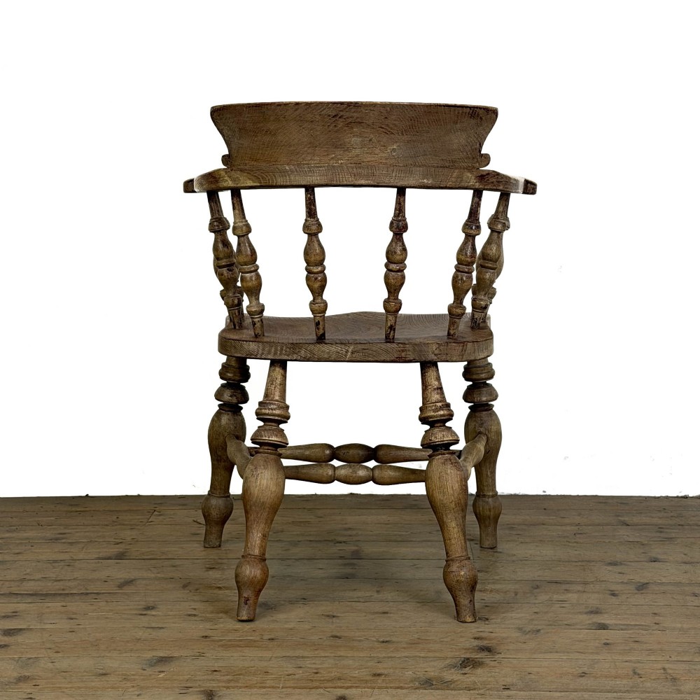 An antique wooden smokers bow armchair with turned spindles, a curved horseshoe armrest, and turned legs. View III