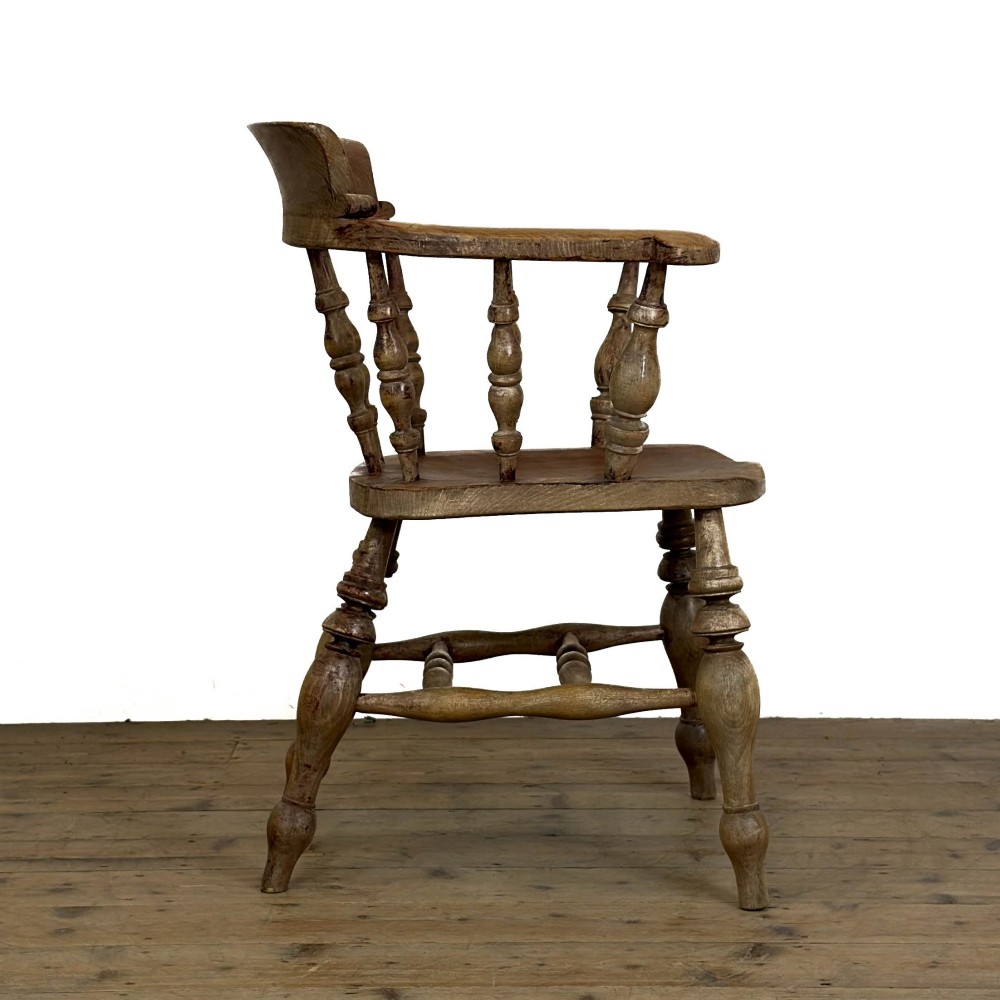 An antique wooden smokers bow armchair with turned spindles, a curved horseshoe armrest, and turned legs. View IV