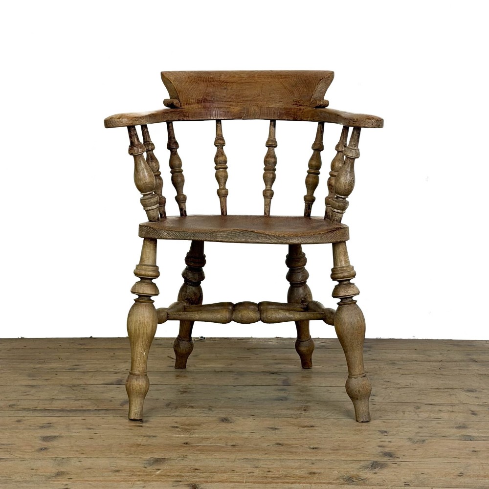An antique wooden smokers bow armchair with turned spindles, a curved horseshoe armrest, and turned legs. View VI