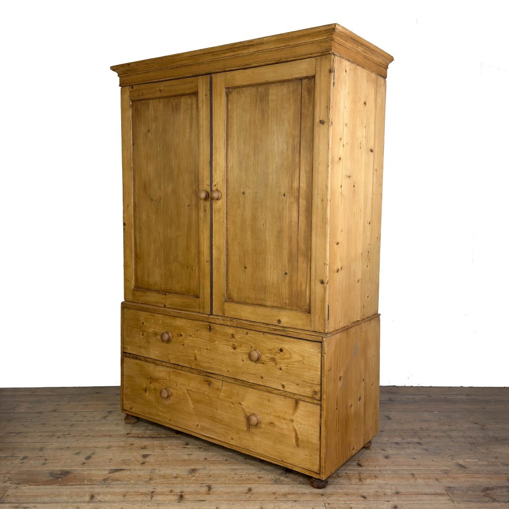 A 19th-century pine linen press featuring a moulded cornice, two upper panelled doors, two wide lower drawers with wooden knob handles, resting on turned bun feet. View II