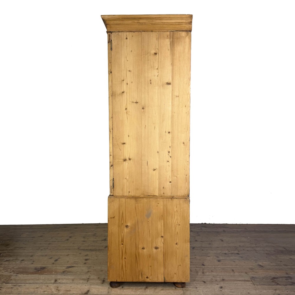 A 19th-century pine linen press featuring a moulded cornice, two upper panelled doors, two wide lower drawers with wooden knob handles, resting on turned bun feet. View III
