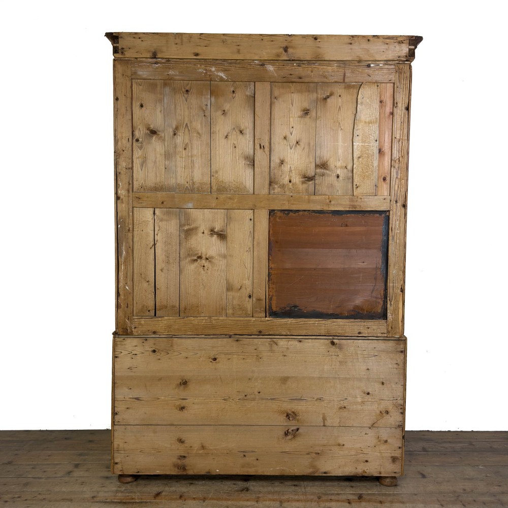 A 19th-century pine linen press featuring a moulded cornice, two upper panelled doors, two wide lower drawers with wooden knob handles, resting on turned bun feet. View IV