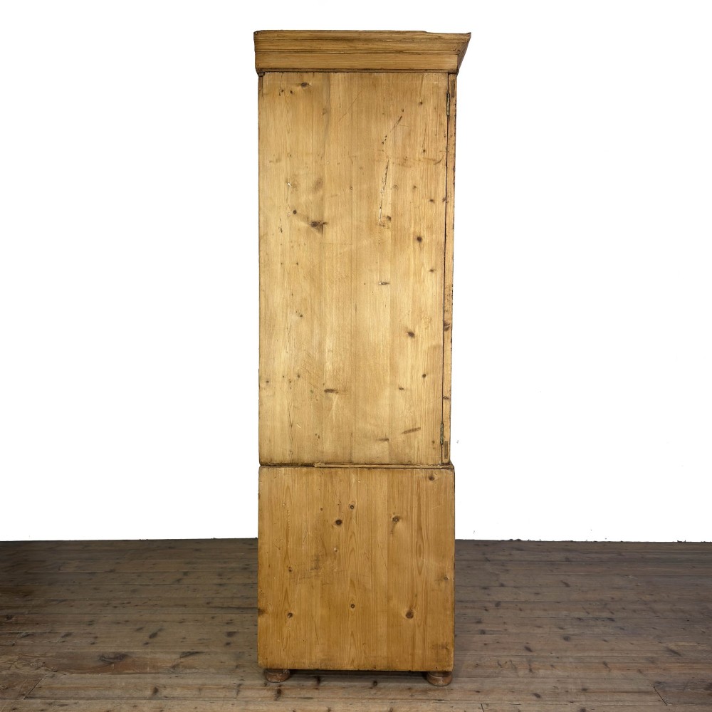 A 19th-century pine linen press featuring a moulded cornice, two upper panelled doors, two wide lower drawers with wooden knob handles, resting on turned bun feet. View V