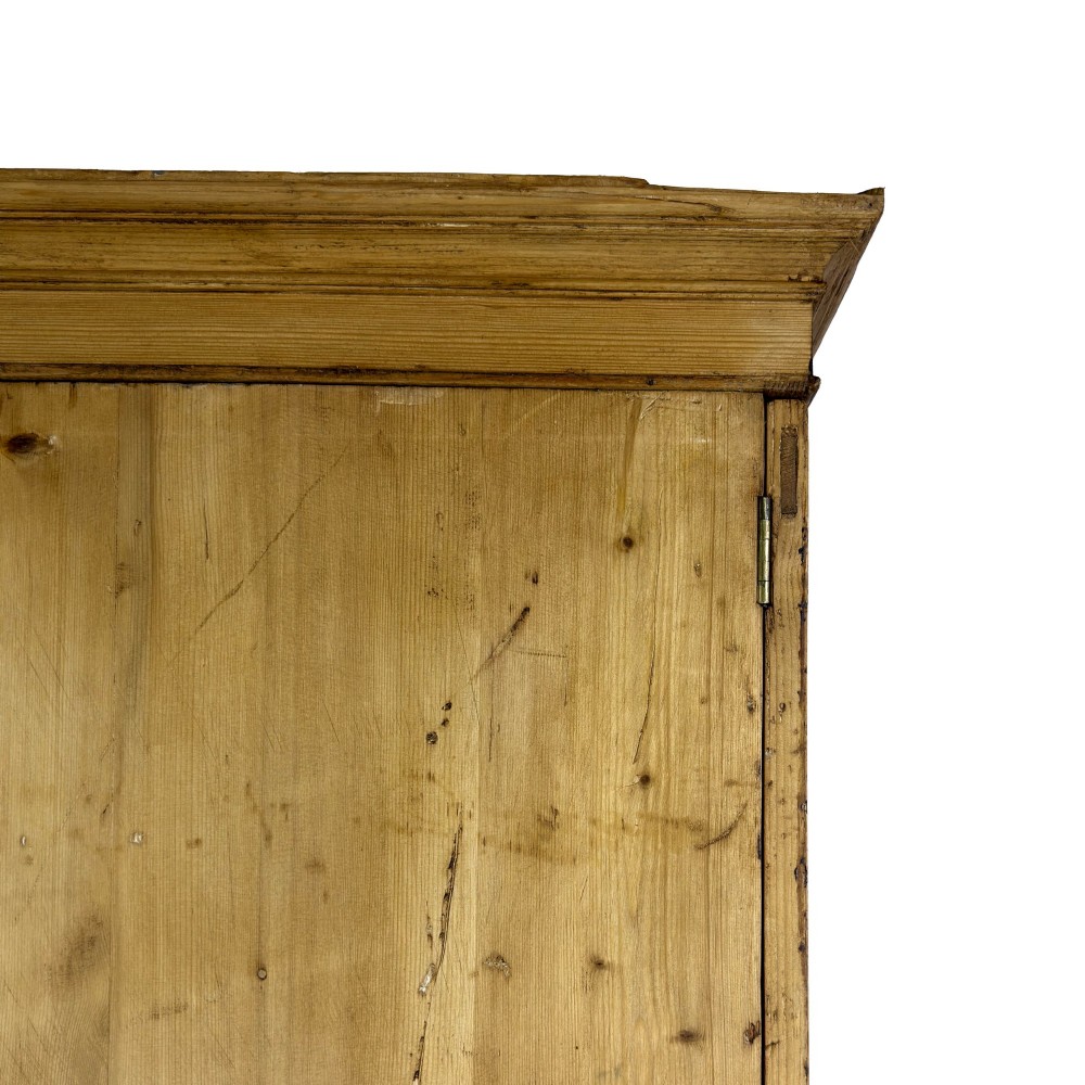 A 19th-century pine linen press featuring a moulded cornice, two upper panelled doors, two wide lower drawers with wooden knob handles, resting on turned bun feet. View VI