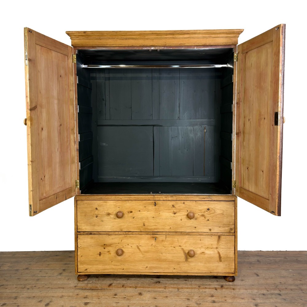 A 19th-century pine linen press featuring a moulded cornice, two upper panelled doors, two wide lower drawers with wooden knob handles, resting on turned bun feet. View VIII