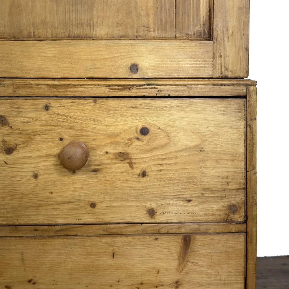 A 19th-century pine linen press featuring a moulded cornice, two upper panelled doors, two wide lower drawers with wooden knob handles, resting on turned bun feet. View IX