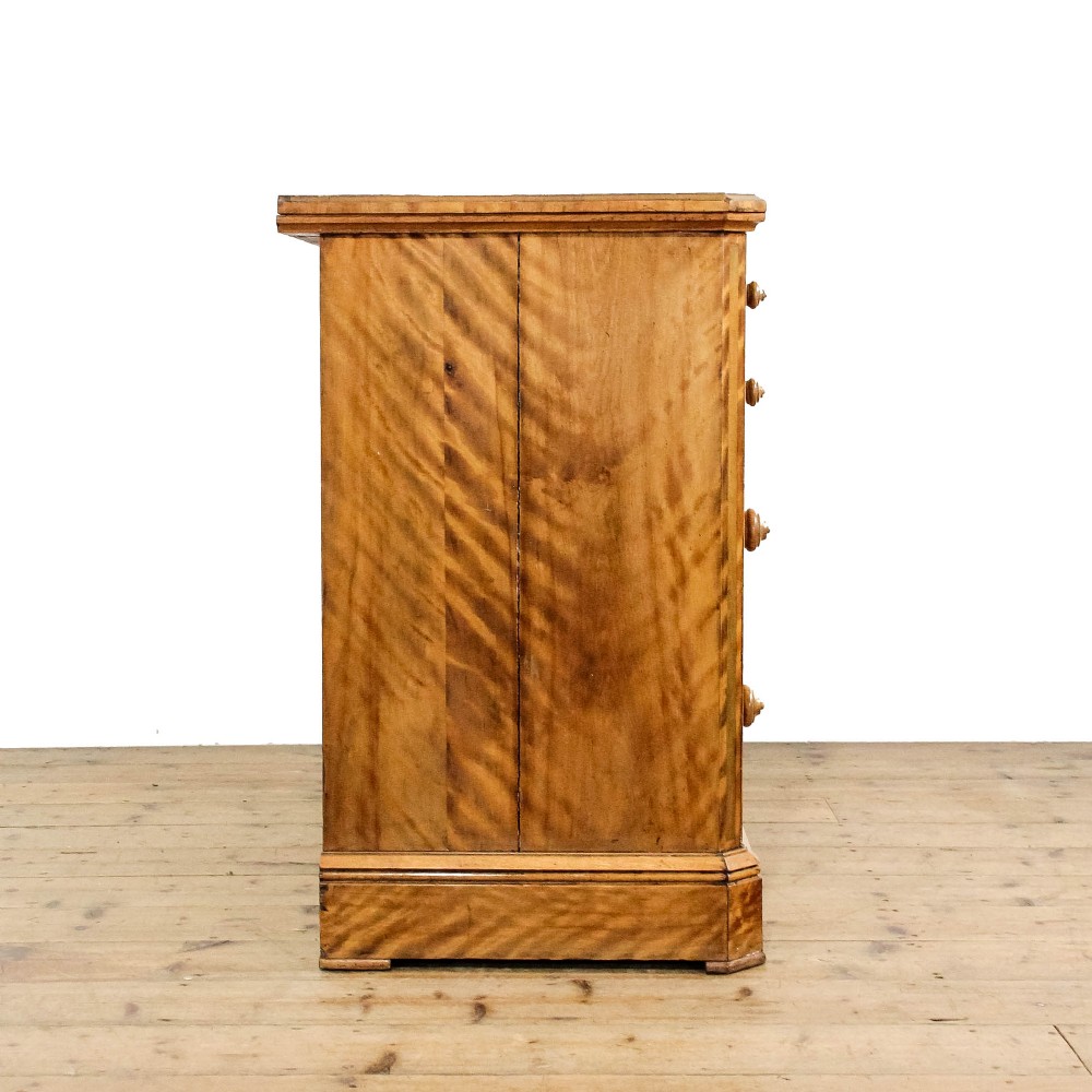 A Victorian satinwood chest of drawers with turned wooden handles, subtle geometric inlaid banding, and a broad plinth base. View II
