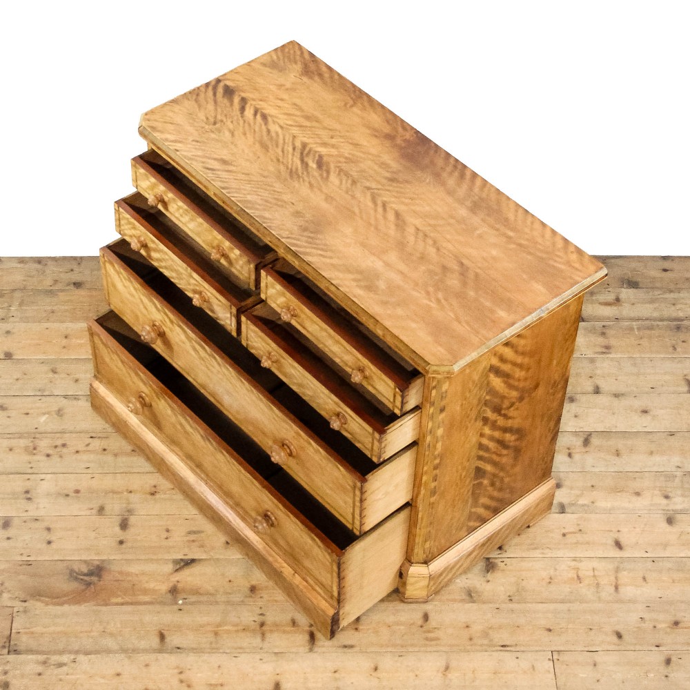 A Victorian satinwood chest of drawers with turned wooden handles, subtle geometric inlaid banding, and a broad plinth base. View V