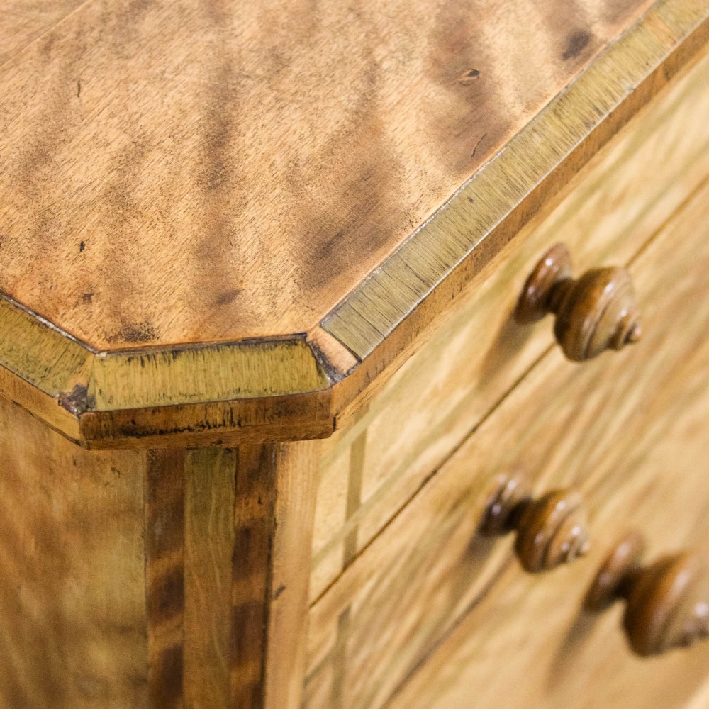 A Victorian satinwood chest of drawers with turned wooden handles, subtle geometric inlaid banding, and a broad plinth base. View IX